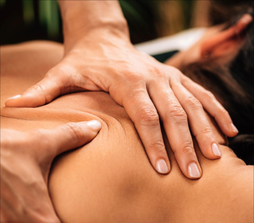 Close up of two hands deeply massaging a person’s right shoulder blade area